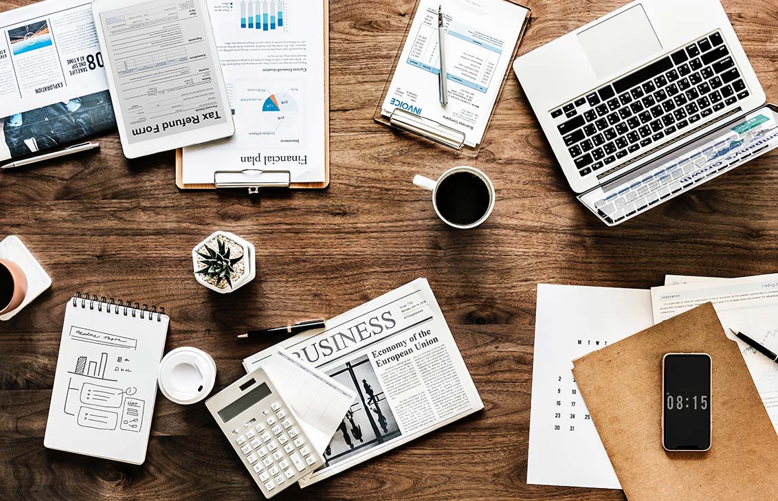 Photo of a desk with coffee, laptop, notebooks, smart phone