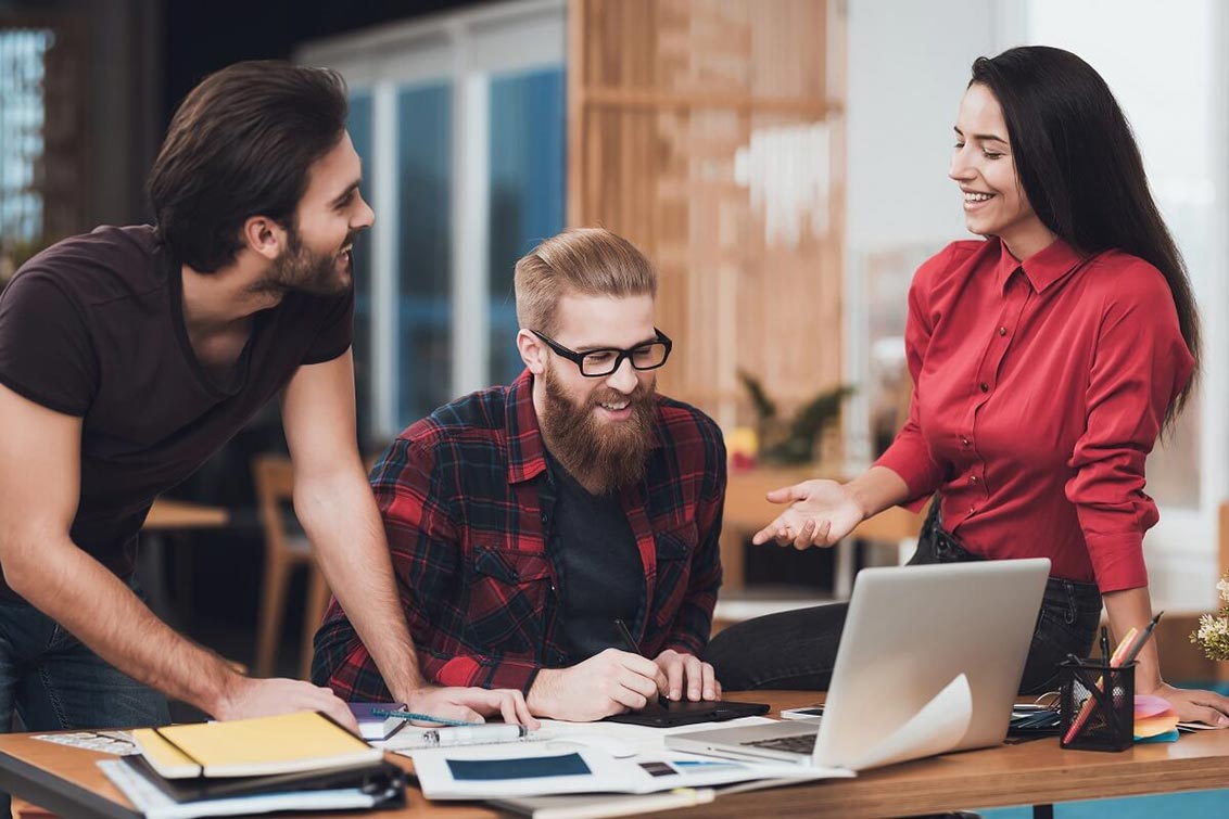 Photo of 3 people looking at a laptop and laughing