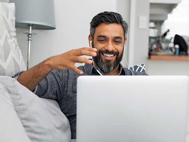 Photo of a man wearing headphones and looking at a laptop